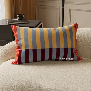 Detailed close-up of a retro striped long throw pillow resting on a cozy cream sofa.