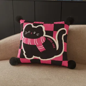 Detailed view of the cute black cat cushion with pink checkered pattern and cozy corner pompoms.
