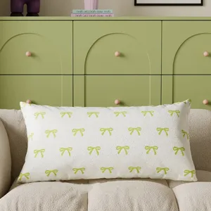 Decorative rectangular throw pillow featuring a green bow print on white fabric for couch.