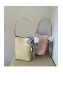 Women summer minimalist bucket bag, chic handbag with ribbon and plush ball pendant.