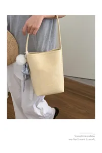 Detailed view of a minimalist yellow bucket bag with pendant, ideal for daily casual wear.