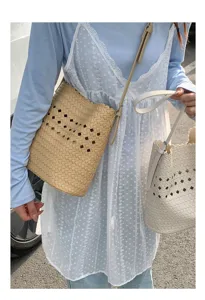 Detailaufnahme von sommerlichen, geflochtenen Eimerentaschen im Freien mit Kleidung.