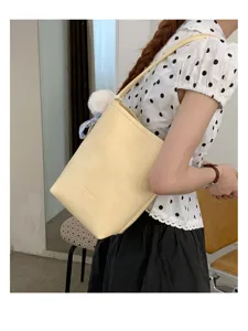 Close-up detail shot of a stylish yellow bucket leather shoulder bag with fluffy charm.