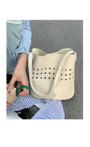 Nahaufnahme der beige geflochtenen Eimer Tasche mit filigranen Rauten-Ausschnittmustern.
