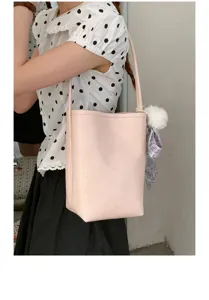 Detail view of stylish pink bucket bag with fluffy charm, versatile everyday shoulder handbag.