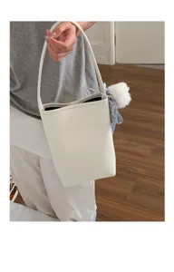 Minimalist white leather bucket bag with shoulder strap, stylish pom-pom and scarf charm.