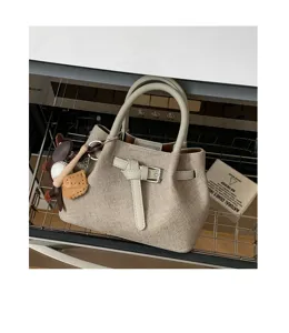 Close-up detail shot of the minimalist canvas handbag with chic buckle and cute charm pendants.