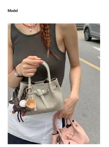 Minimalist textured handbag with belt detail and cute pendants, chic crossbody tote bag.