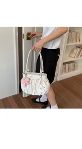 Vue détaillée du sac porté épaule blanc à pois colorés et joli accessoire nœud rose.