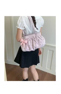 Vue détaillée du sac sous les bras plissé rose à pois colorés et joli pendentif nœud.
