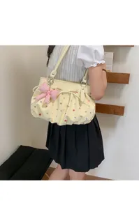 Vue détaillée d'un sac à épaule jaune à pois colorés et pendentif nœud mignon et charmant.