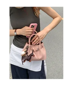 Detail view of the elegant pink mini tote bag with cute animal charm and chic belt design.