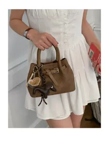 Minimalist brown textured handbag for women, chic tote with cute dog charm and belt detail.