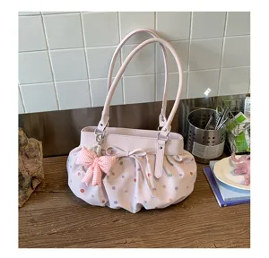 Vue détaillée du sac à épaule plissé à pois roses avec un joli nœud et des poignées.