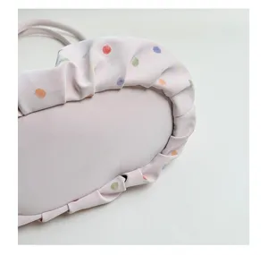 Gros plan détaillé du sac plissé sous les bras à pois colorés, cuir PU rose clair.