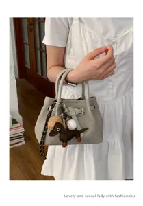 Minimalist small handbag with cute dachshund and baseball charms for women detail view.