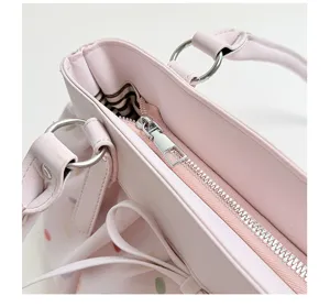 Vue détaillée de la fermeture éclair et des anneaux de sac cabas plissé rose à pois.