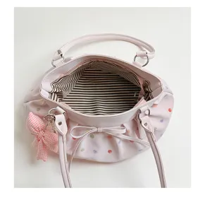 Vue détaillée de l'intérieur du sac rose plissé, motif à pois colorés et doublure rayée.