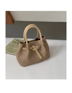 Textured canvas handbag detail featuring double top handles, chic buckle strap and clean stitching.