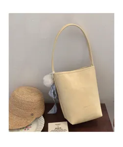 Summer niche textured leather bucket bag with shoulder strap and chic charm accessory detail.