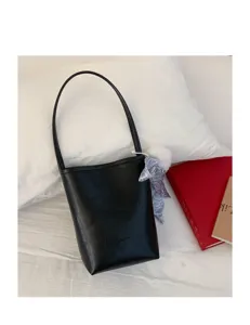Detail view of a minimalist black PU leather bucket bag with shoulder strap and chic charm.