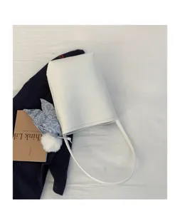 White minimalist bucket shoulder bag with scarf and pom-pom charm detail in daily style.