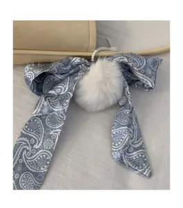 Chic blue paisley ribbon bag charm with soft white pom pom for stylish women handbag decoration.