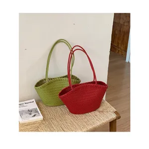Vista dettagliata della borsa a spalla intrecciata in verde e rosso, ambientazione.