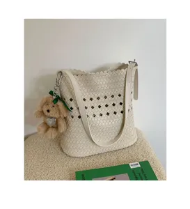Nahaufnahme der weißen geflochtenen Eimer Tasche mit eleganten Ausschnittdetails und Anhänger.