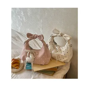 Detail view of stylish polka dot hobo shoulder bags with cute bow handle and heart charm.