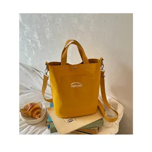 Vue détaillée du sac seau en toile jaune montrant la poche avant et la bandoulière.
