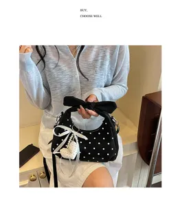 Chic black polka dot crescent shoulder bag with elegant bow knot and pearl heart pendant.
