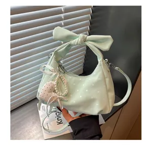 Detailed view of women fashion mint green polka dot crescent shoulder bag with bow handle.