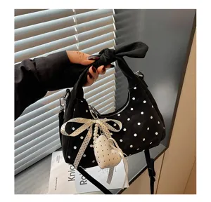 Detailed view of the stylish polka dot hobo bag with bow handle and heart pearl pendant.
