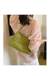 Detail view of a stylish green woven leather underarm handbag with chic geometric cutouts.