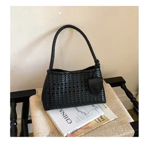 Detailed view of black woven leather shoulder bag, stylish hollow-out underarm commuting handbag.
