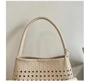 Close-up detail of beige woven hollow-out shoulder handbag showing fine lattice texture.