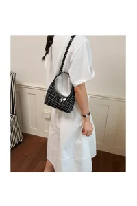 Detailed shot of a stylish black and white polka dot crescent bag worn on shoulder.