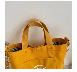 Vue détaillée du sac cabas en toile jaune avec poignées doubles et poche frontale.