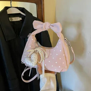 Women pink polka dot hobo bag with bow handle and cute heart pearl charm for daily fashion use.