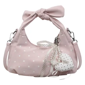 Stylish pink polka dot hobo bag featuring bow handle and pearl pendant for women daily.