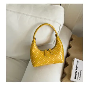 Yellow polka dot hobo handbag detail, minimalist patent leather style, chic fashion accessory.
