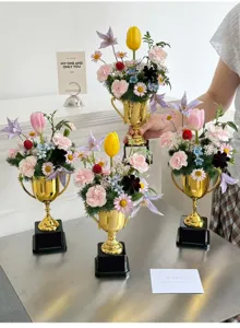 Detailed view of creative golden trophy vase flower arrangement DIY material and decor display.