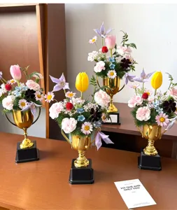 Detailed view of creative golden trophy flower arrangement decor with mixed floral bouquets.