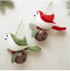 Close-up detail of cute felt bird Christmas tree hanging ornaments with metal bells and pine.