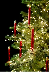 Nahaufnahme roter Glas-Weihnachtsbaumkerzen mit Goldklammern und warmen Lichterketten.
