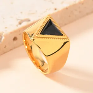 Nahaufnahme des goldenen Edelstahlrings mit schwarzem Dreiecksstein und feiner Musterung.