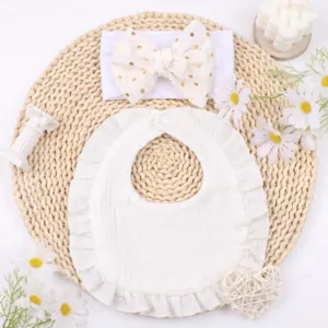Set bavaglino neonato e fascia fiocco in cotone bianco con dettagli volant graziosi.