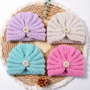 Close-up detail of four cute baby knitted turban hats with pearl flower, multi-color.