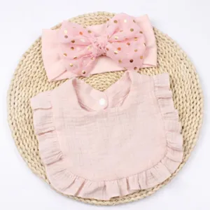 Vista dettagliata del set fascia e bavaglino rosa per neonati con fiocco e cotone morbido.